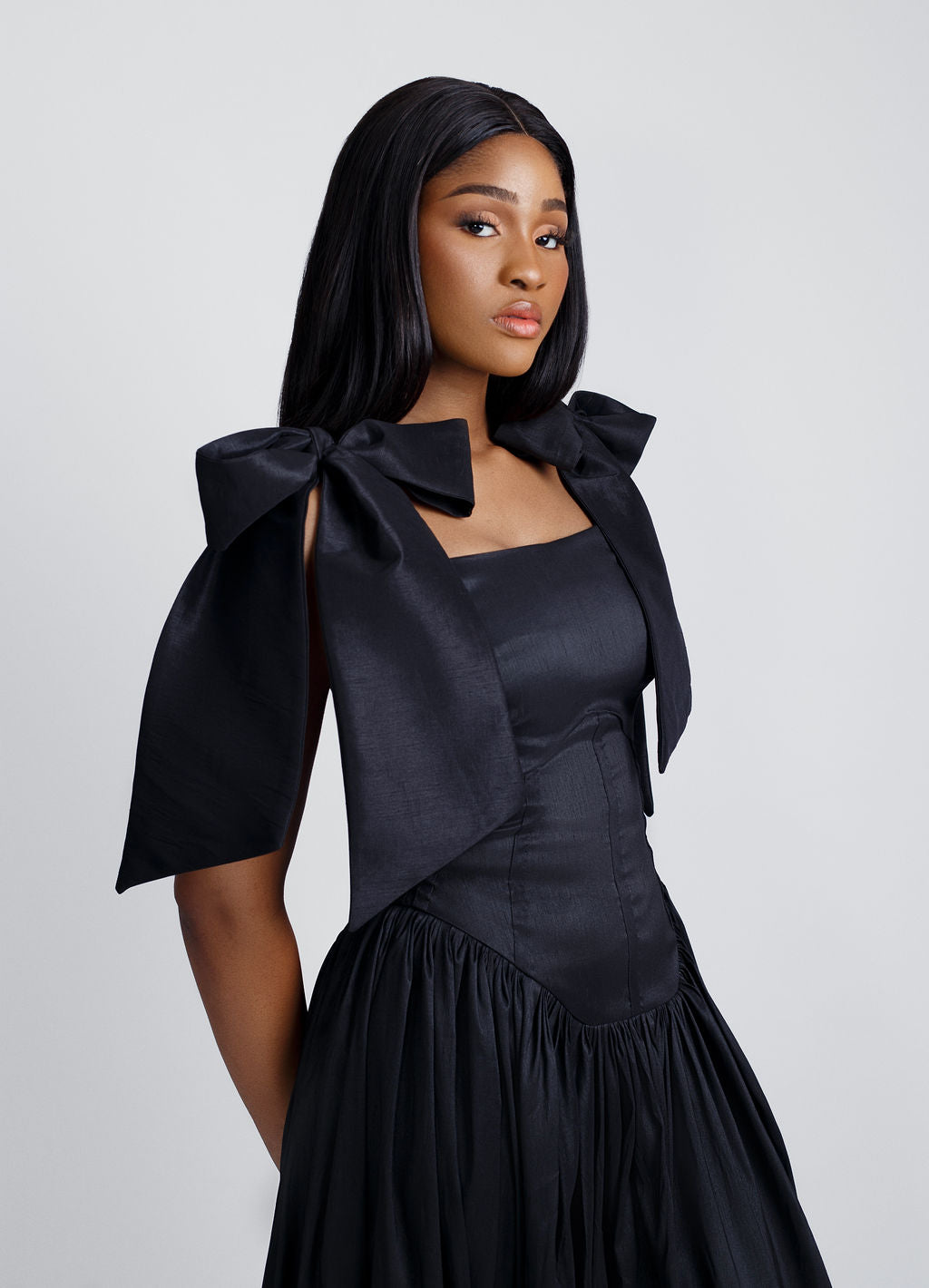 Chic black maxi dress with delicate bow straps, flowing effortlessly for a sleek and sophisticated look. The minimalist design adds elegance, making it perfect for upscale gatherings or stylish evening wear.