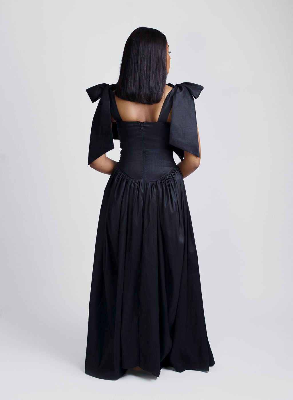 The back view of Black maxi dress with elegant bow straps, designed for modern women who love timeless fashion. This versatile dress combines minimalist style with luxurious comfort, perfect for evening events, formal occasions, or chic everyday wear. Shop now for trendy women's clothing at Kaiiko and Virgo.