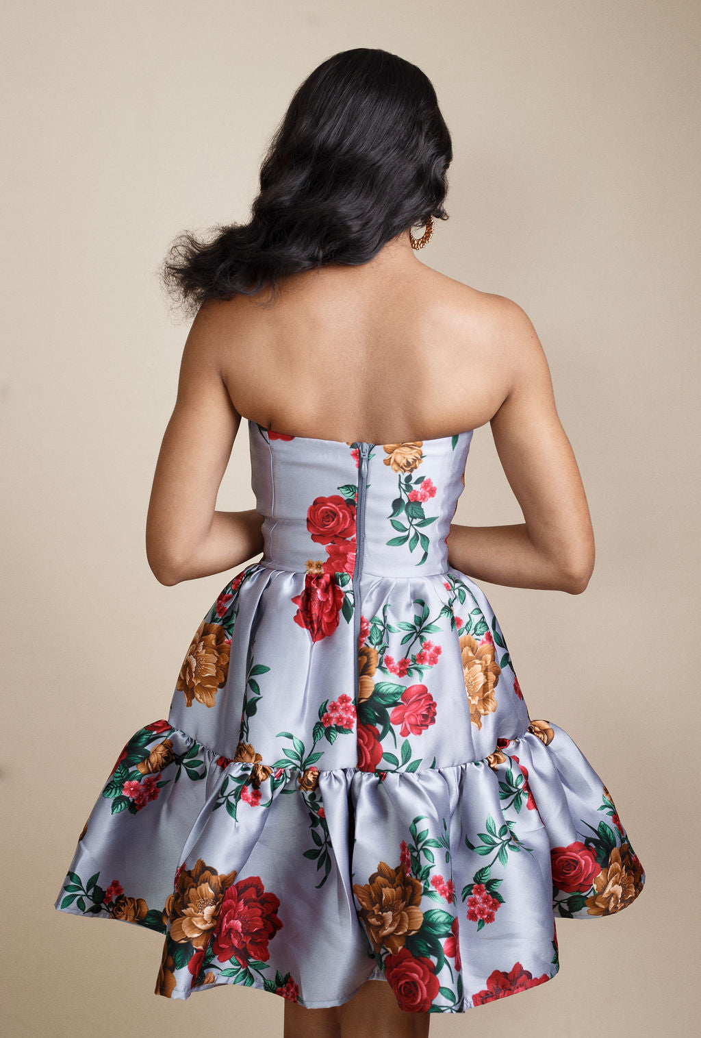Back view of Stylish grey strapless floral dress with bold red flower prints, featuring a flirty flared skirt above the knee. Ideal for weddings, cocktail parties, and special occasions. Discover elegant occasion dresses and trending women’s fashion for 2025 at Kaiiko and Virgo.